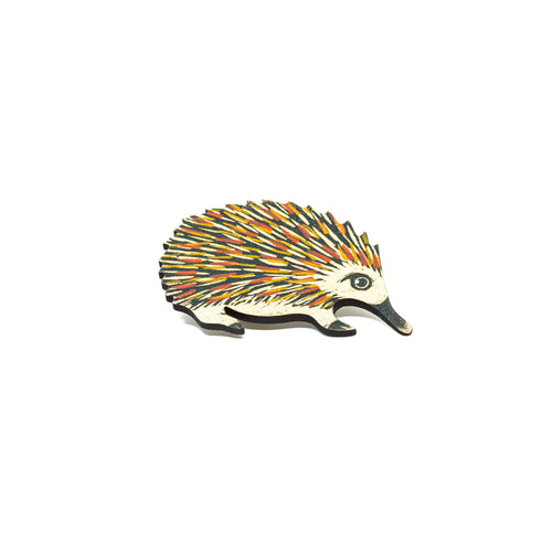 Handcrafted wooden echidna brooch, painted red, yellow and black.